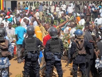 Anti-riot police looks on at protestors in Kampala